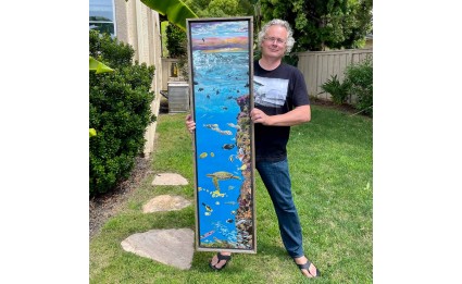 Artist Roy Kerckhoffs holding up 14x60" Hawaii Reef image on canvas
