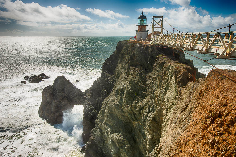 suspension bridge and point bonita lighthouse and natural arch with crashing wave