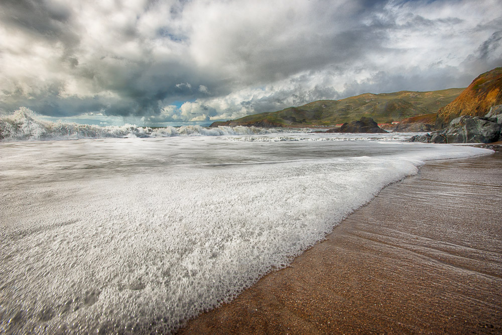 waves and foam on south rodeo beach with dark clouds